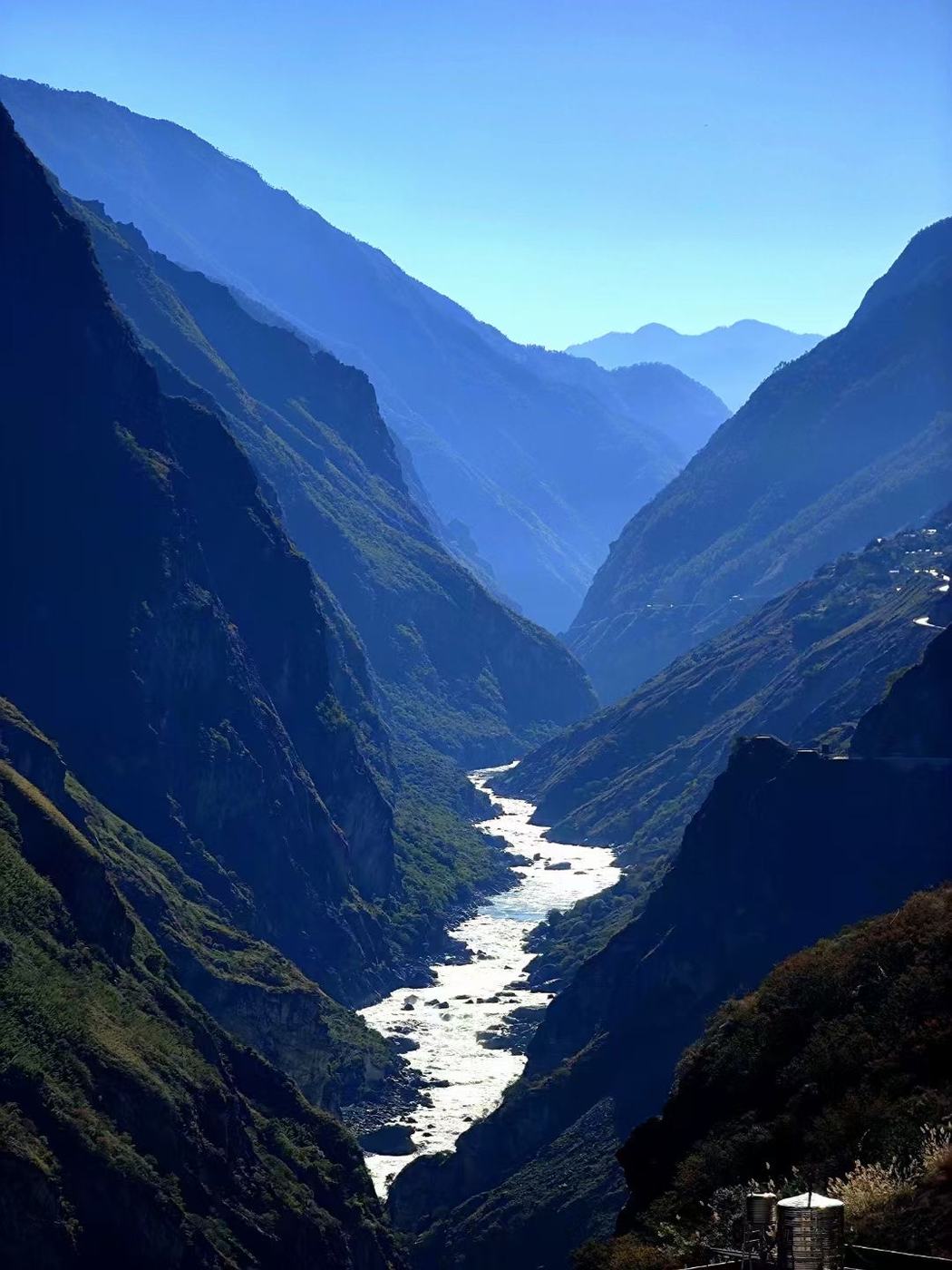 A narrow river between steep, hazy blue gorge walls