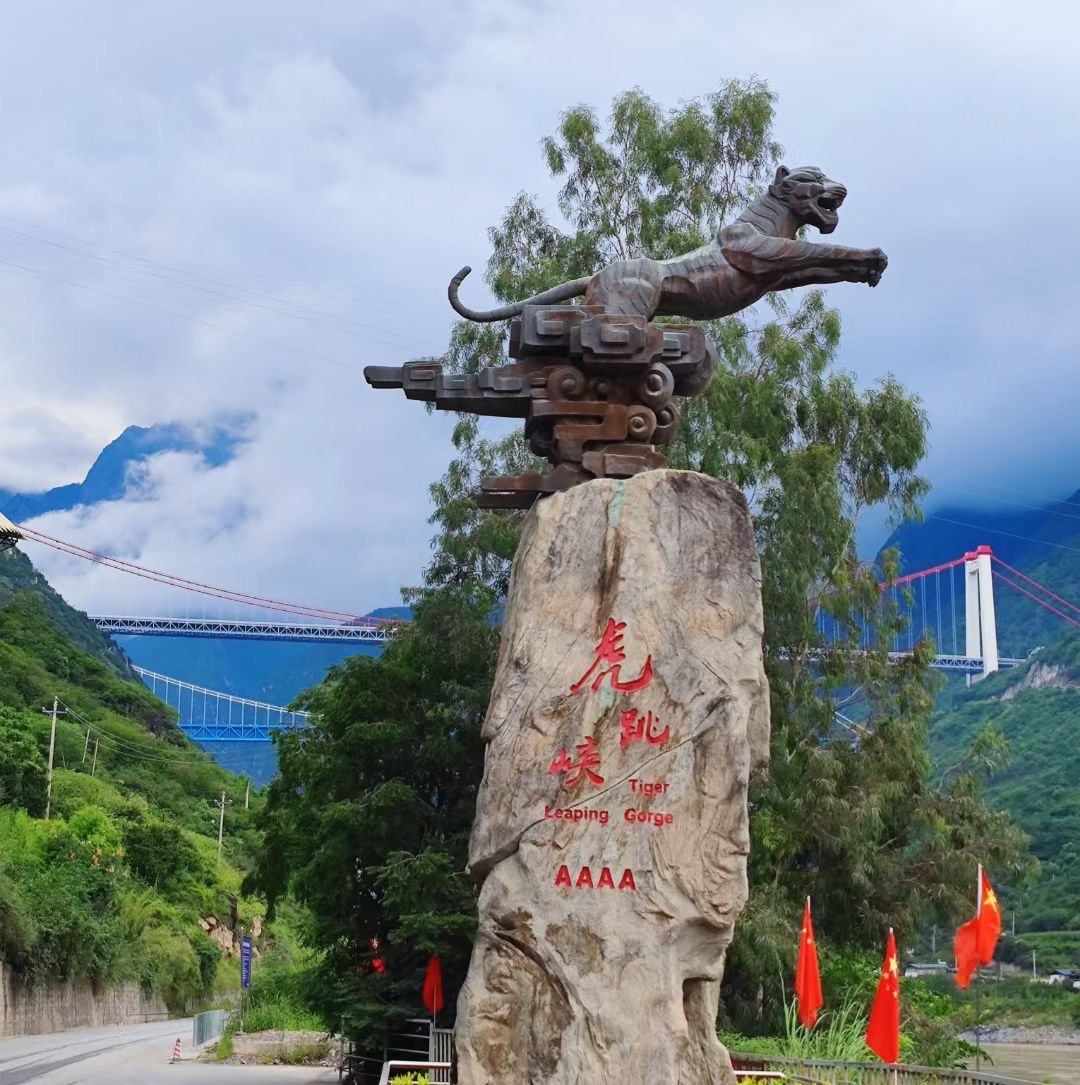 The tiger monument at the gorge entrance with the red characters for Tiger Leaping Gorge and bridges behind