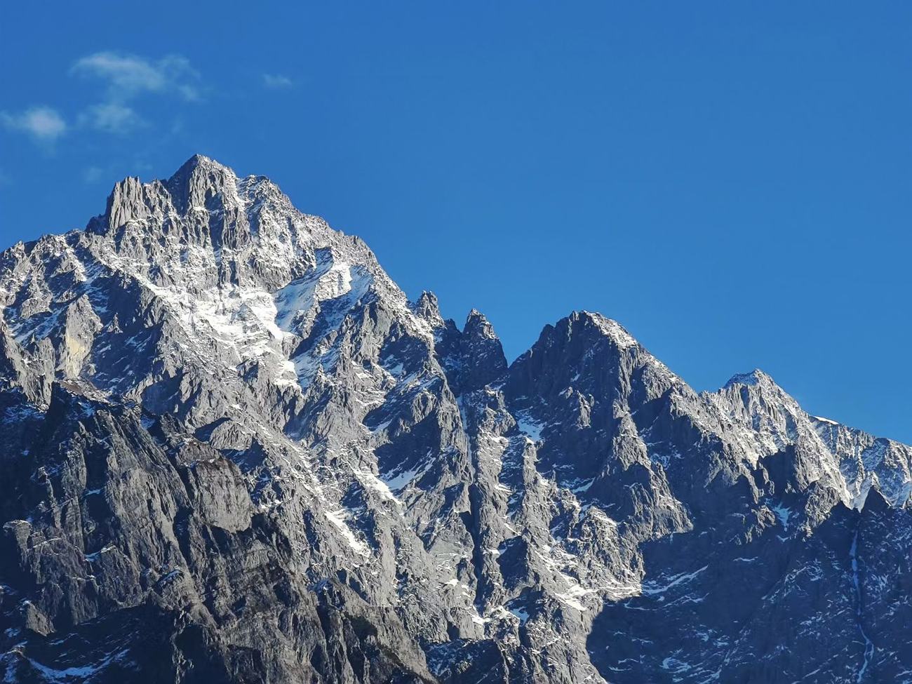 Snow-dusted rock summit under a deep blue sky